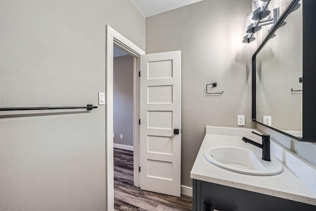 bathroom featuring baseboards, wood finished floors, and vanity