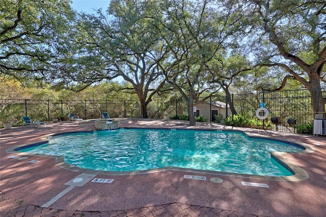 view of swimming pool with a pool with connected hot tub, fence, and a patio