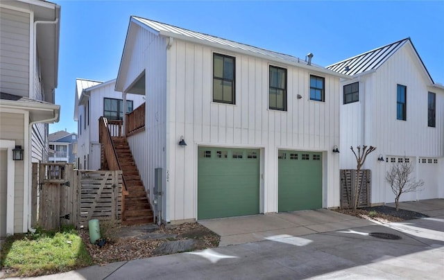 view of front facade featuring a garage, driveway, metal roof, a standing seam roof, and stairs