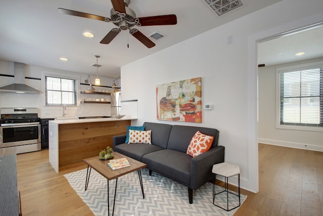 living room with light wood-style floors, baseboards, visible vents, and recessed lighting