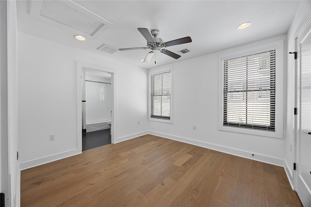 unfurnished bedroom featuring attic access, visible vents, multiple windows, and wood finished floors