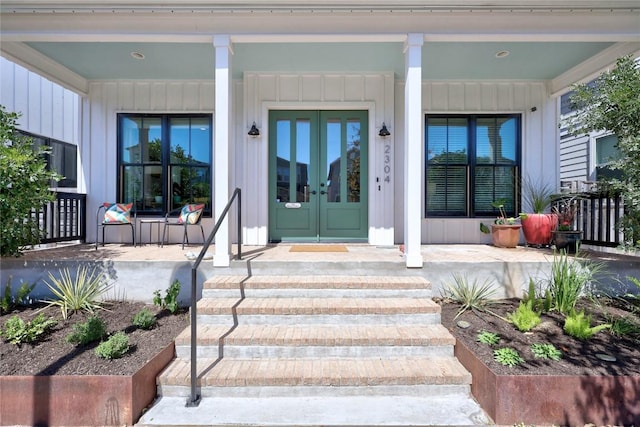 view of exterior entry with board and batten siding, french doors, and covered porch