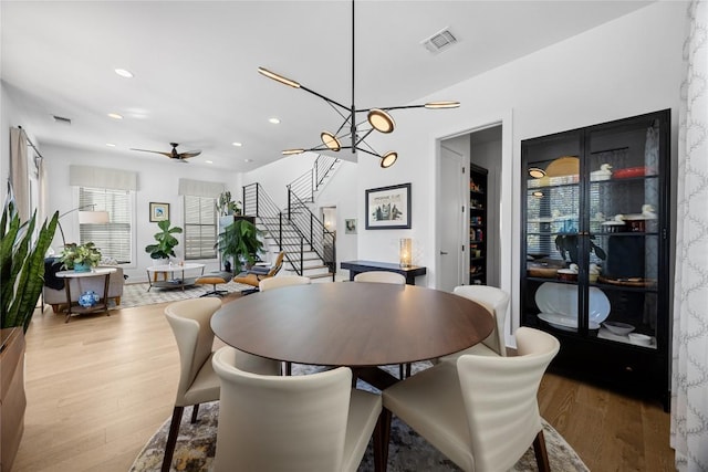 dining space featuring wood finished floors, visible vents, and stairs