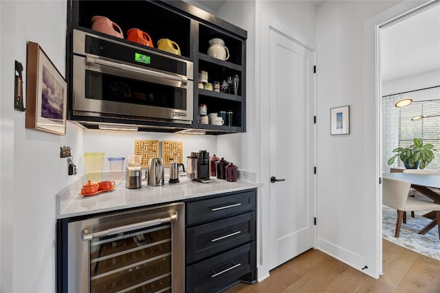 bar featuring beverage cooler, a dry bar, and light wood-style floors