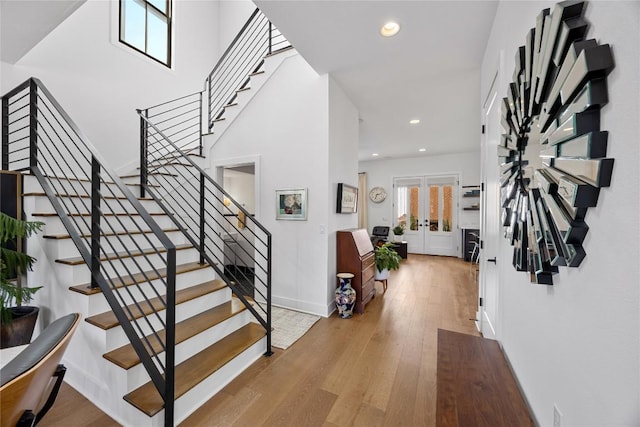 entrance foyer with light wood finished floors, baseboards, stairway, french doors, and recessed lighting