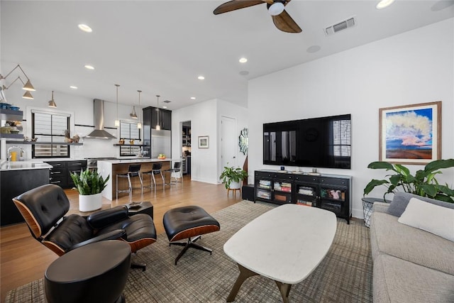 living room featuring a ceiling fan, light wood-type flooring, visible vents, and recessed lighting