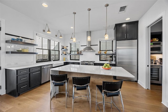 kitchen with beverage cooler, visible vents, appliances with stainless steel finishes, wall chimney range hood, and open shelves