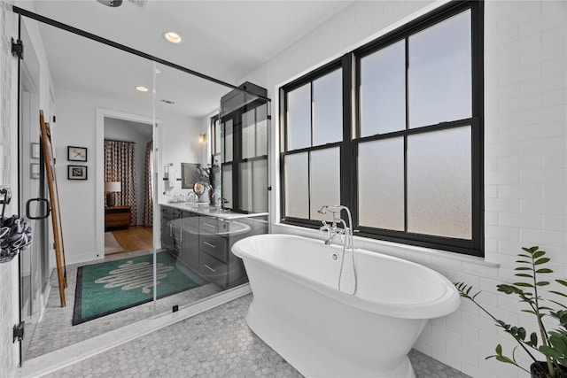 full bath with tile patterned floors, a freestanding tub, vanity, and recessed lighting