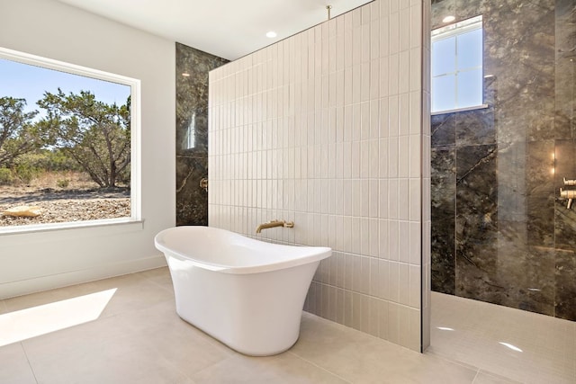 bathroom featuring a freestanding bath, a walk in shower, tile walls, and tile patterned floors