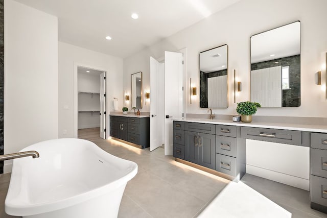 bathroom featuring recessed lighting, a spacious closet, a freestanding bath, and vanity