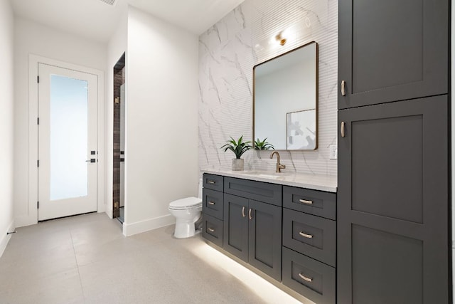 bathroom with toilet, baseboards, and vanity