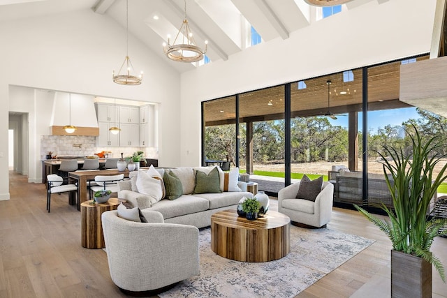 living area with light wood-style floors, a wealth of natural light, a chandelier, and beamed ceiling