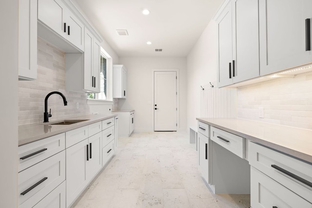 kitchen featuring marble finish floor, light countertops, visible vents, white cabinetry, and a sink