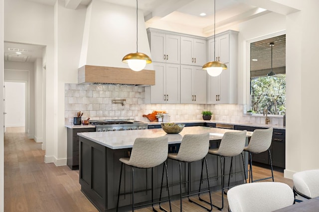 kitchen with decorative backsplash, premium range hood, and light wood finished floors