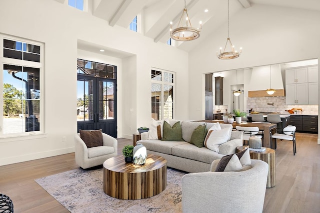 living room featuring a chandelier, high vaulted ceiling, baseboards, light wood-style floors, and beamed ceiling