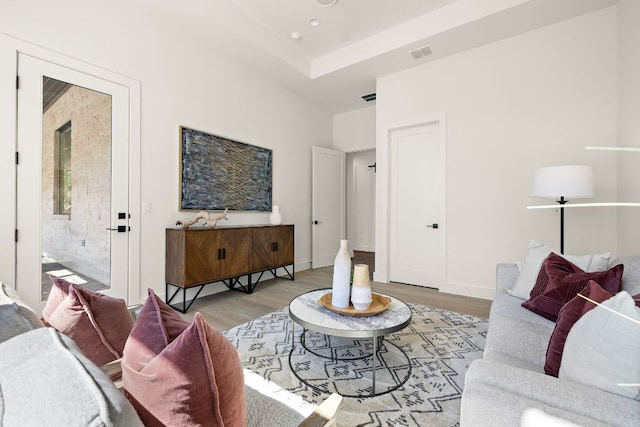 living room featuring visible vents, light wood-style flooring, and baseboards