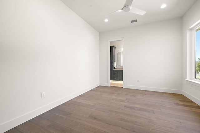 empty room with wood finished floors, a ceiling fan, and baseboards