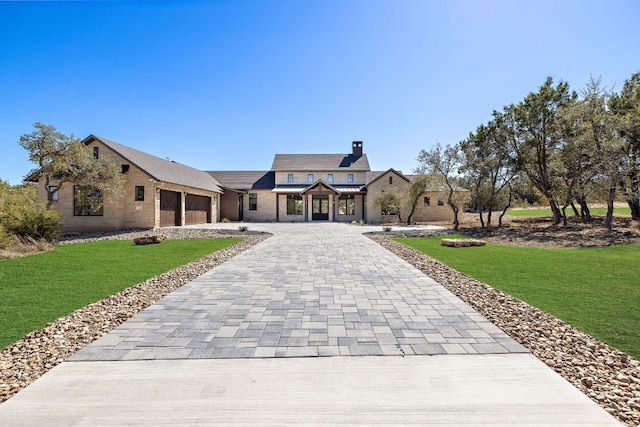 view of front of home featuring a front yard, decorative driveway, an attached garage, and a standing seam roof