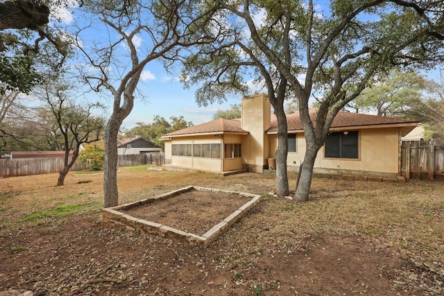 back of property with fence private yard, a sunroom, and a chimney