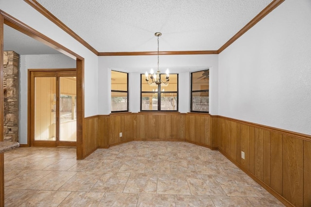 unfurnished room featuring a wainscoted wall, a notable chandelier, wooden walls, and a textured ceiling