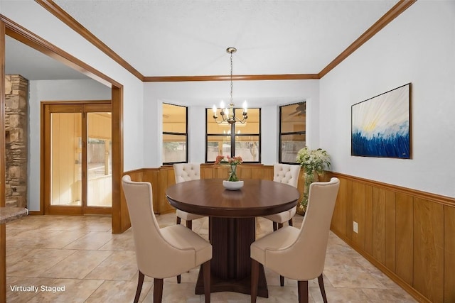 dining space with ornamental molding, a chandelier, wainscoting, and wooden walls