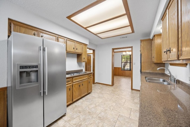 kitchen with visible vents, a textured ceiling, electric stovetop, stainless steel refrigerator with ice dispenser, and a sink