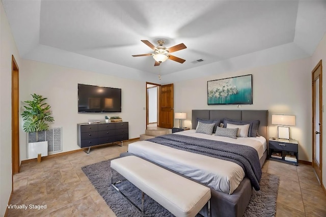 bedroom featuring a tray ceiling, visible vents, and baseboards