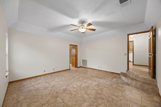 spare room with baseboards, a textured ceiling, visible vents, and a ceiling fan