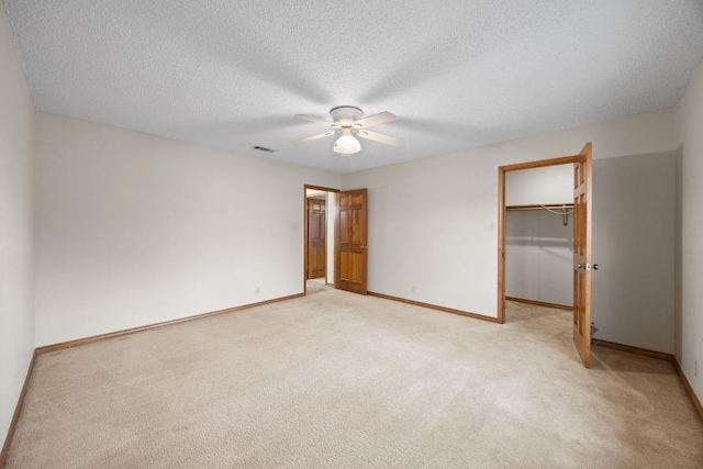 unfurnished bedroom featuring visible vents, baseboards, light colored carpet, a walk in closet, and a closet