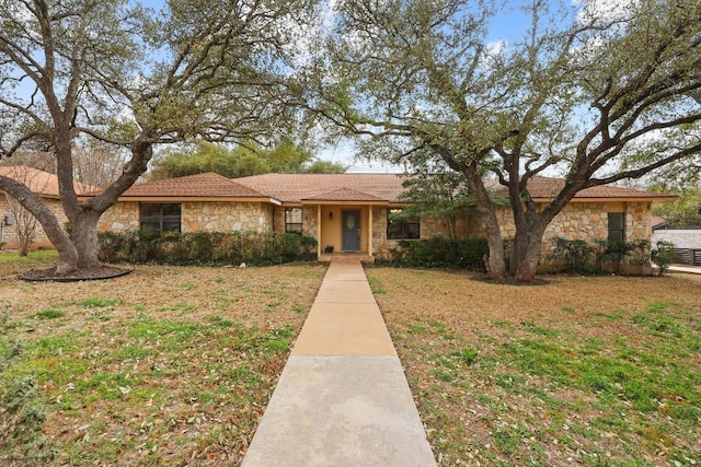 single story home featuring stone siding and a front yard