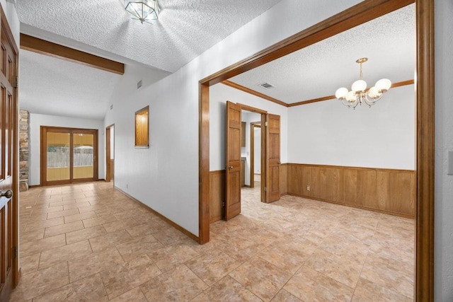 interior space with a textured ceiling, a chandelier, vaulted ceiling with beams, visible vents, and wainscoting