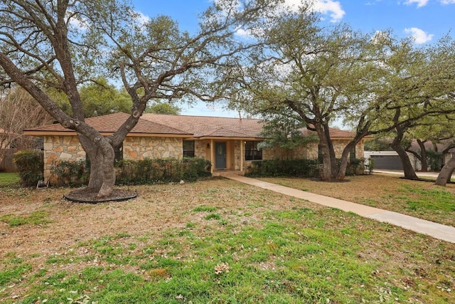 ranch-style home with a front yard and stone siding