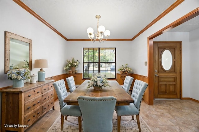 dining room featuring a wainscoted wall, wooden walls, a chandelier, and crown molding