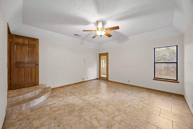 spare room with visible vents, a tray ceiling, ceiling fan, and baseboards