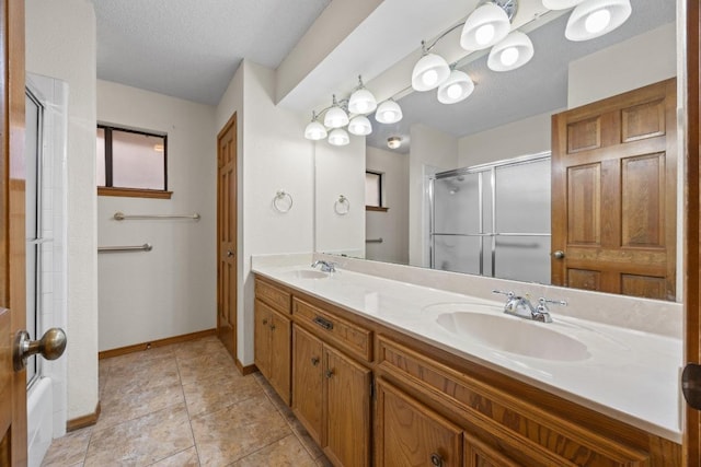 full bathroom featuring double vanity, an enclosed shower, a sink, a textured ceiling, and tile patterned floors