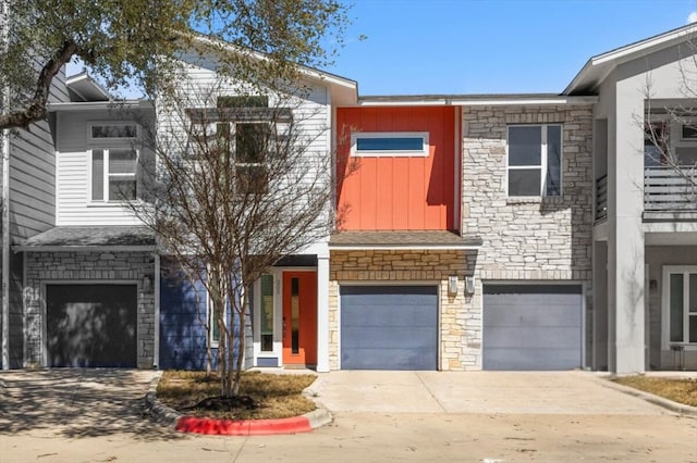 multi unit property with an attached garage, stone siding, board and batten siding, and concrete driveway