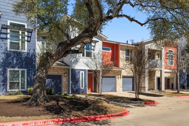 multi unit property with a garage, driveway, and stone siding