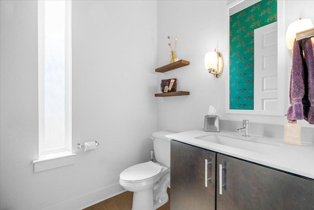 half bathroom with toilet, baseboards, and vanity