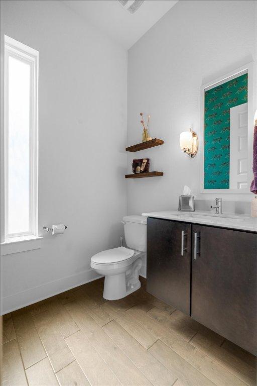 bathroom with baseboards, vanity, toilet, and wood finished floors