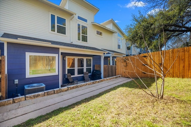 rear view of property featuring fence, central AC unit, and a yard