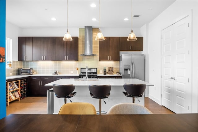 kitchen featuring stainless steel appliances, light countertops, visible vents, a sink, and wall chimney exhaust hood