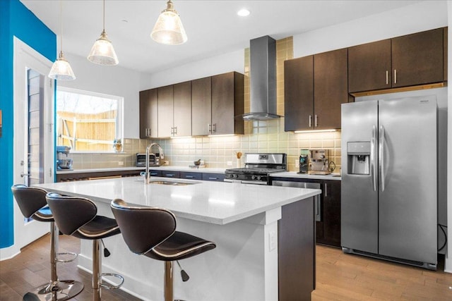 kitchen featuring stainless steel appliances, a kitchen breakfast bar, light wood-style flooring, and wall chimney exhaust hood