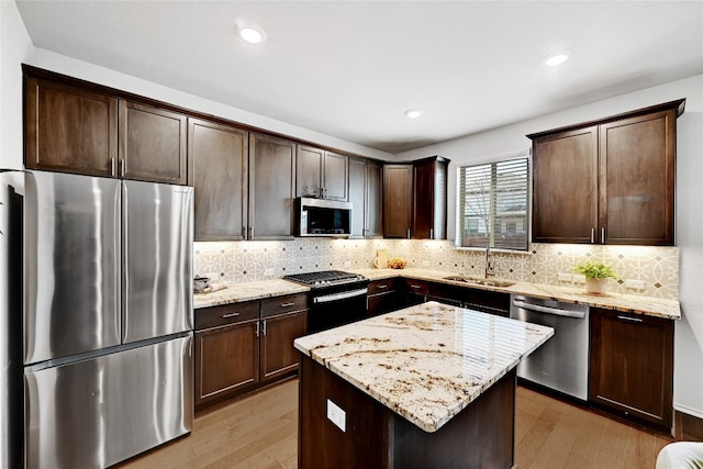 6808 Ellsworth Walk, Austin, TX 78724 - kitchen featuring appliances with stainless steel finishes, dark brown cabinets, light wood finished floors, light stone countertops, and tasteful backsplash