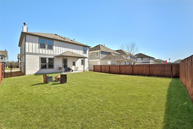 rear view of property with a fenced backyard, a chimney, board and batten siding, and a yard