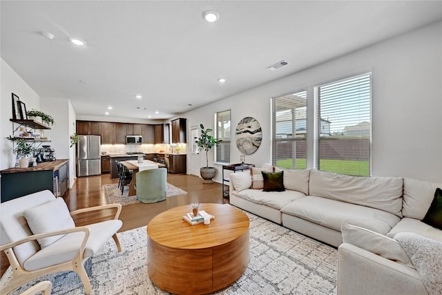 living room featuring light wood-style flooring, visible vents, and recessed lighting