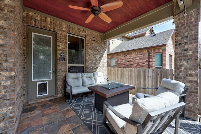 view of patio with fence, a ceiling fan, and an outdoor living space with a fire pit