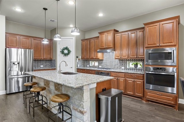 kitchen with visible vents, appliances with stainless steel finishes, brown cabinetry, a sink, and under cabinet range hood