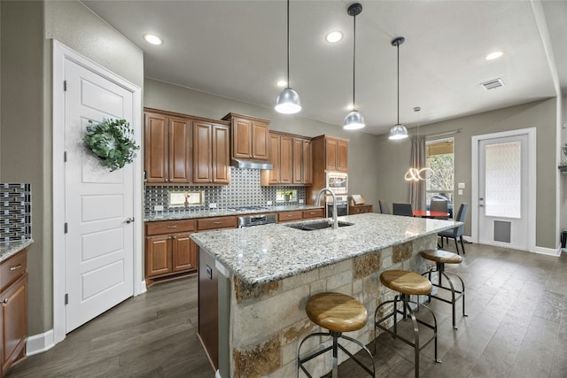 kitchen with stainless steel appliances, backsplash, a sink, and brown cabinets