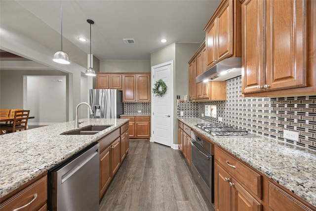 kitchen featuring visible vents, brown cabinetry, appliances with stainless steel finishes, under cabinet range hood, and a sink