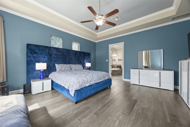 bedroom featuring visible vents, a tray ceiling, and wood finished floors